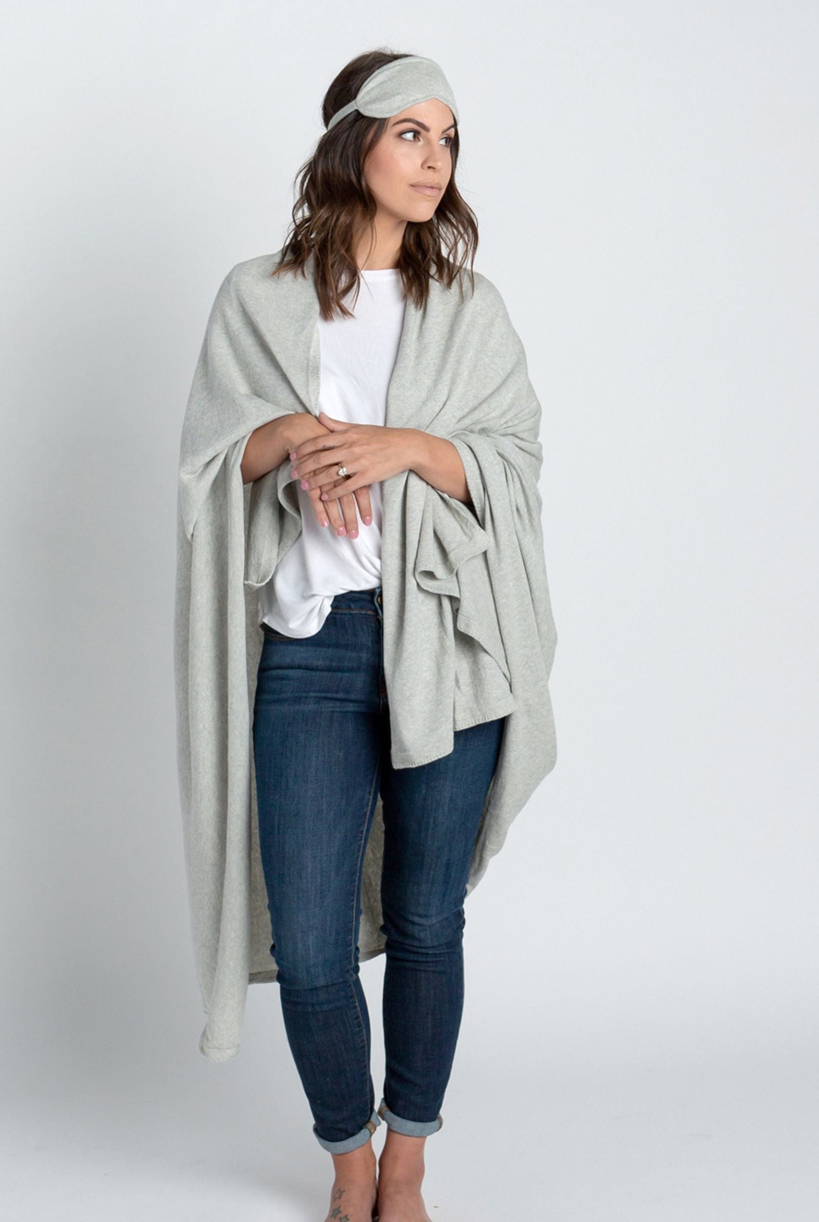 Woman shown wearing Light Gray Travel Set blanket and eye mask
